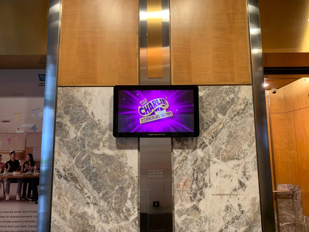 Digital billboard above the Design Orchard entrance on Orchard Road, Singapore, showing a GRAVITY concert ad